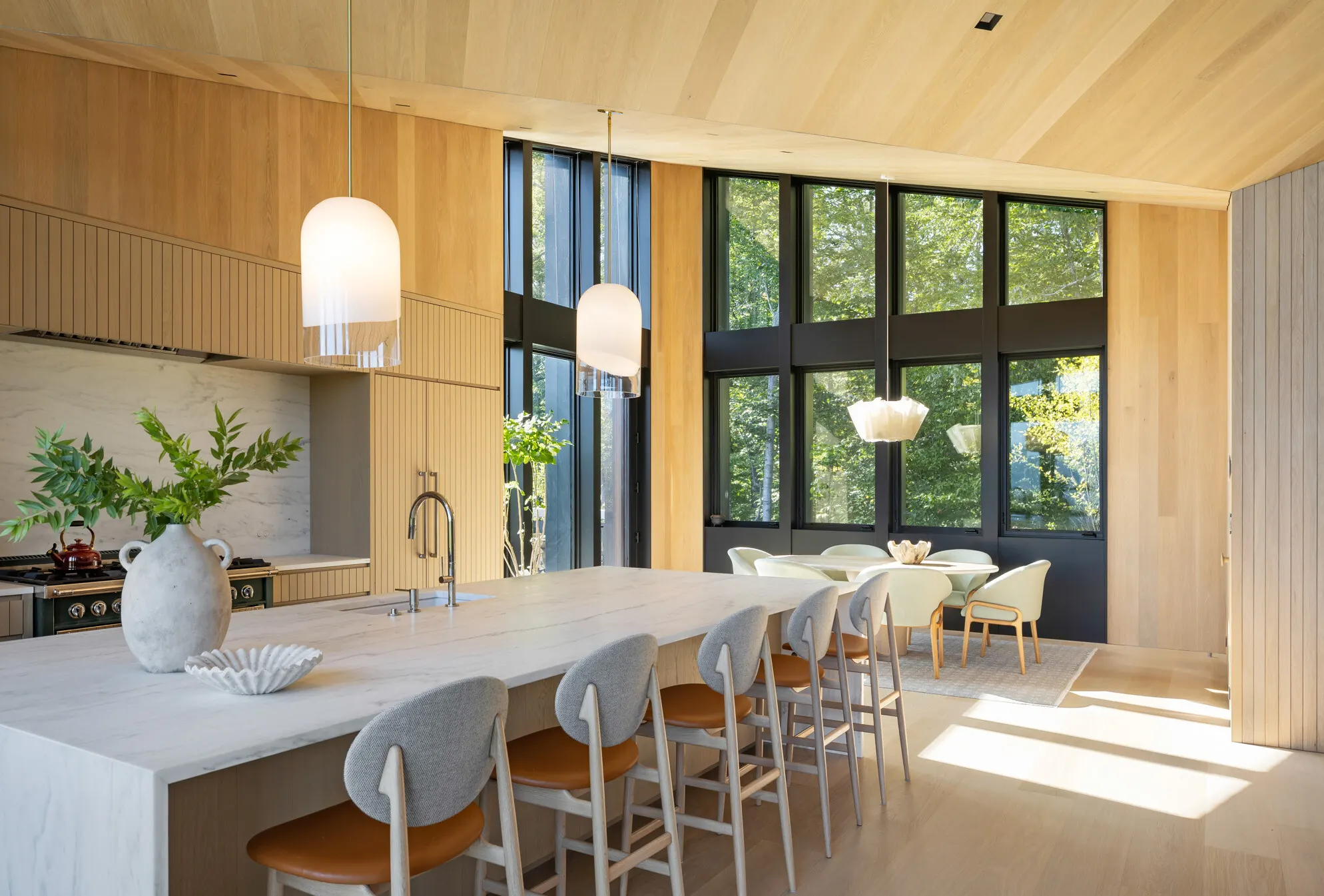 A Stowe kitchen with pale wood ceilings, white pendants and tall black-framed windows