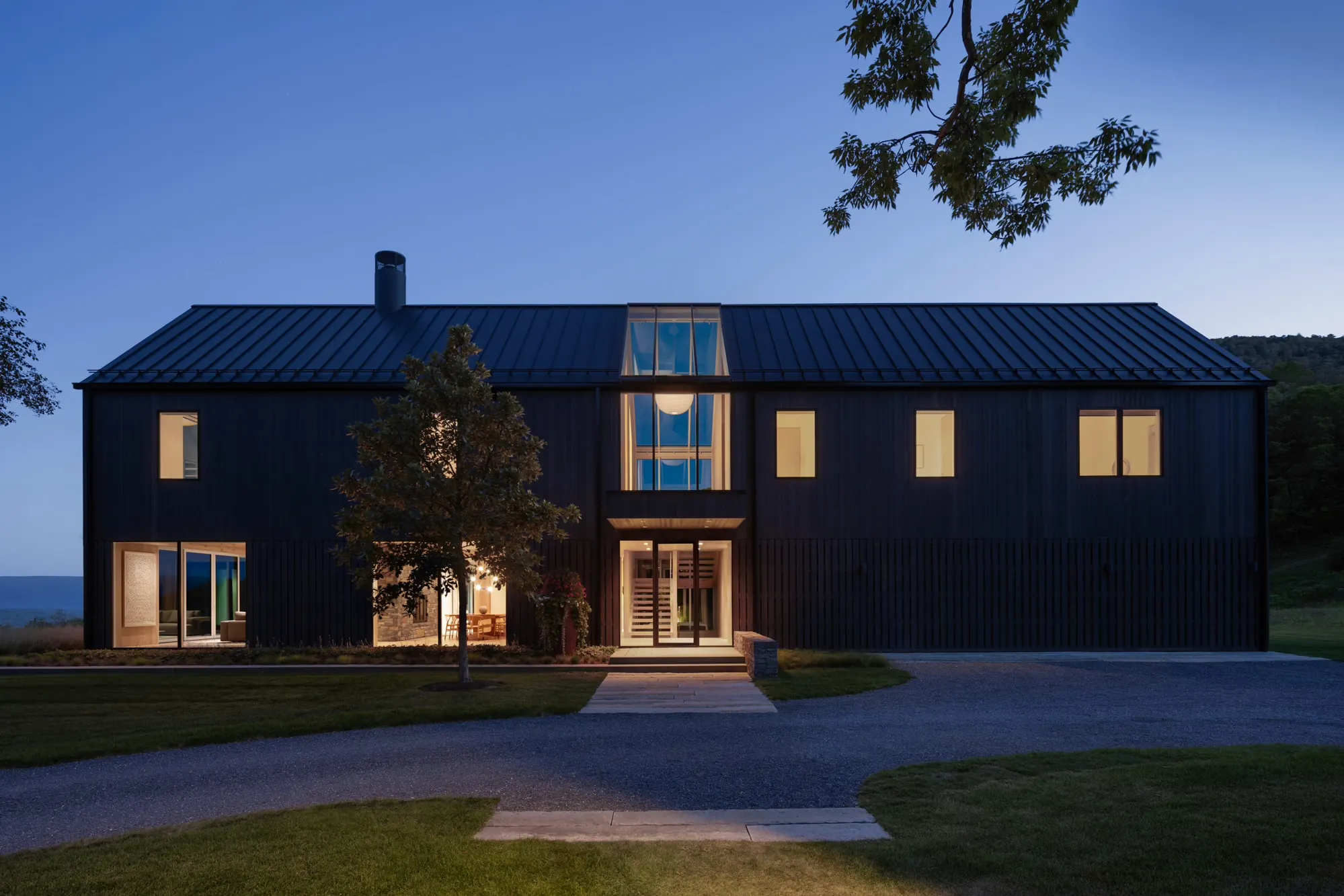 A dark-sided southern Vermont residence lit from within at dusk